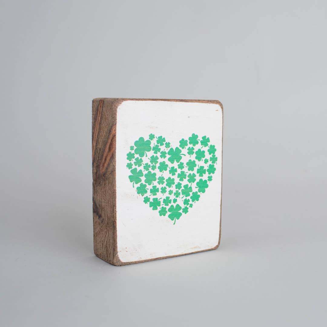 Wooden block with a white background and green heart-shaped pattern of clovers on a gray background