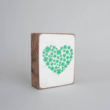 Wooden block with a white background and green heart-shaped pattern of clovers on a gray background