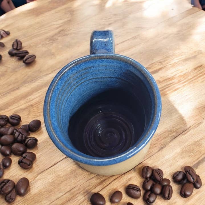 Blue ceramic mug on a wooden table with coffee beans around