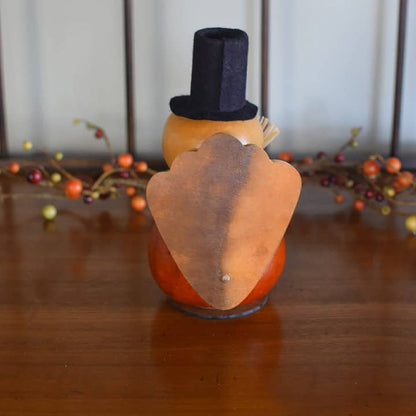 Decorative turkey with a top hat on a wooden surface with blurred background