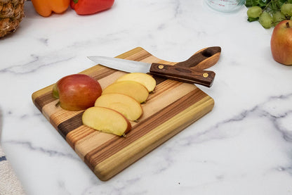 Wooden handled cutting board with sliced apples and a knife on a marble surface.