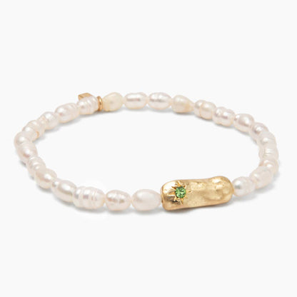 Pearl bracelet with gold bar and green gemstone on a white background. 