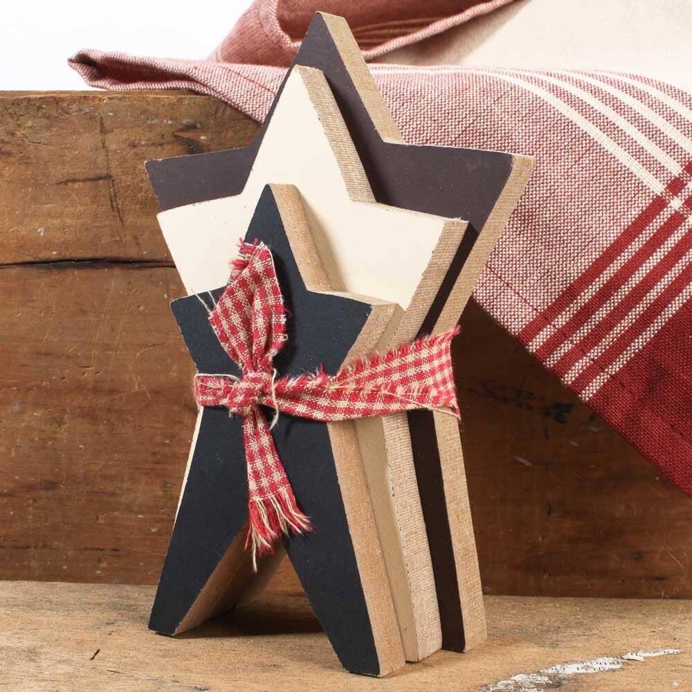 Stack of wooden star-shaped cutouts tied with a red plaid ribbon on a wooden surface.