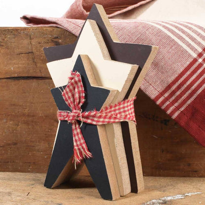 Stack of wooden star-shaped cutouts tied with a red plaid ribbon on a wooden surface.