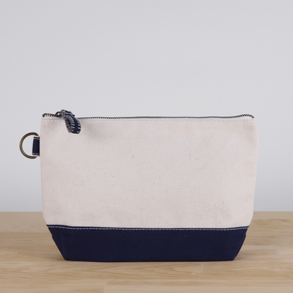 Beige and navy pouch on a wooden surface with a light gray background