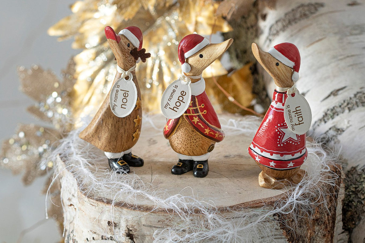 Three decorative duck figurines wearing Santa hats on a wooden base with a festive background.