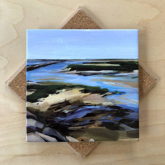 Square trivet with a coastal landscape design on a wooden surface
