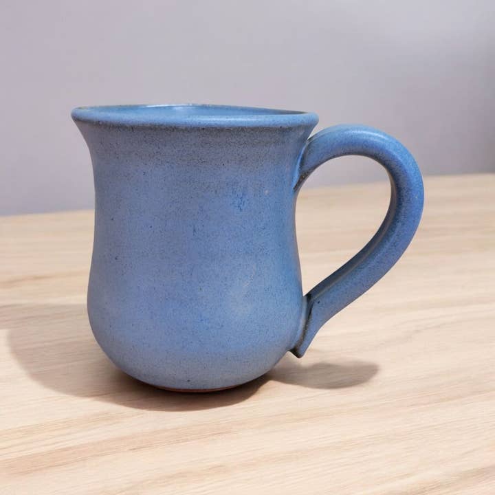 Blue ceramic mug on a wooden surface with a light gray background