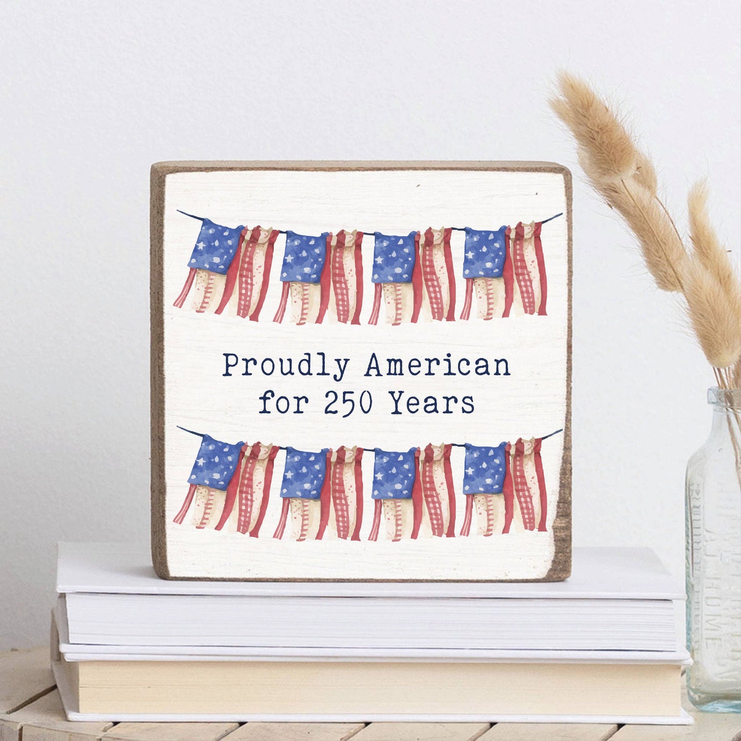 Decorative sign with American flags and text on a stack of books.