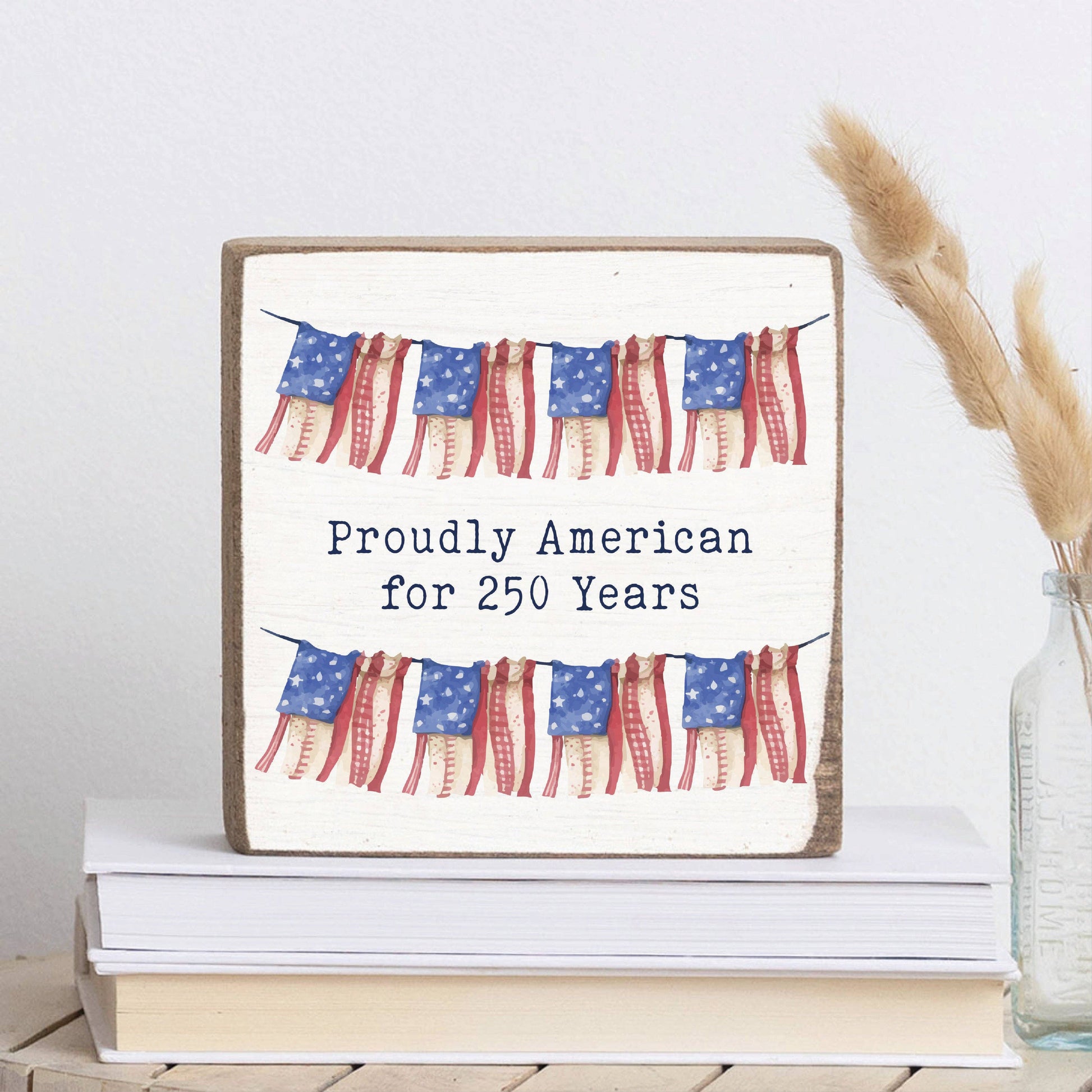 Decorative sign with American flags and text on a stack of books.