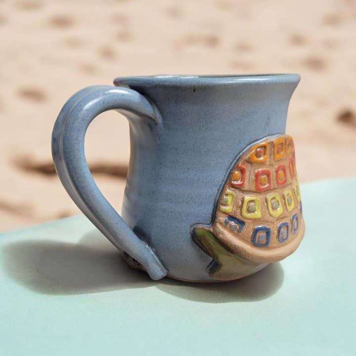 Ceramic mug with a colorful geometric turtle design on a light surface