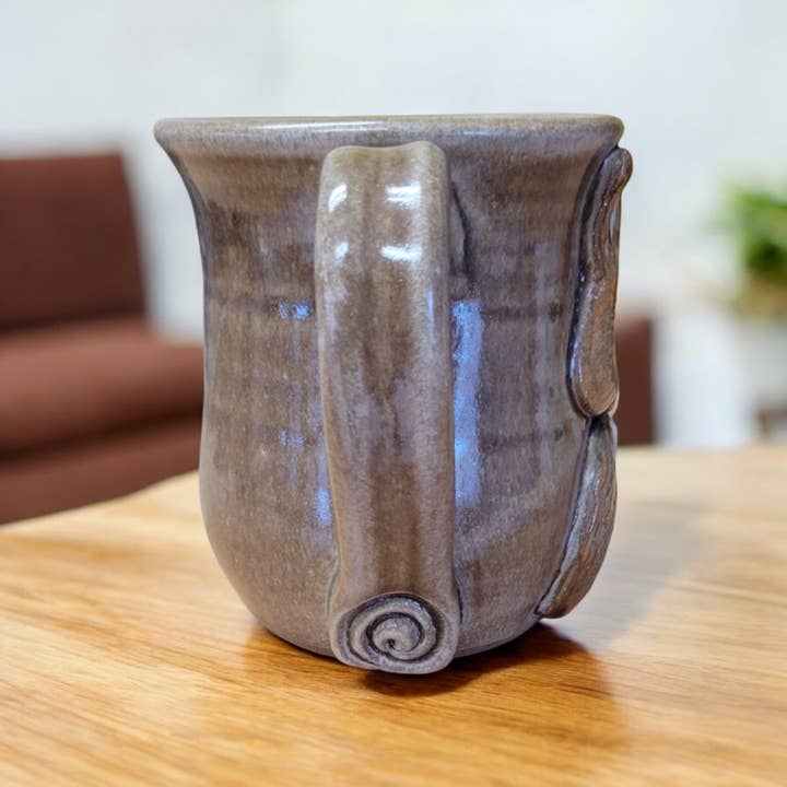 Ceramic mug with a unique handle design on a wooden table.