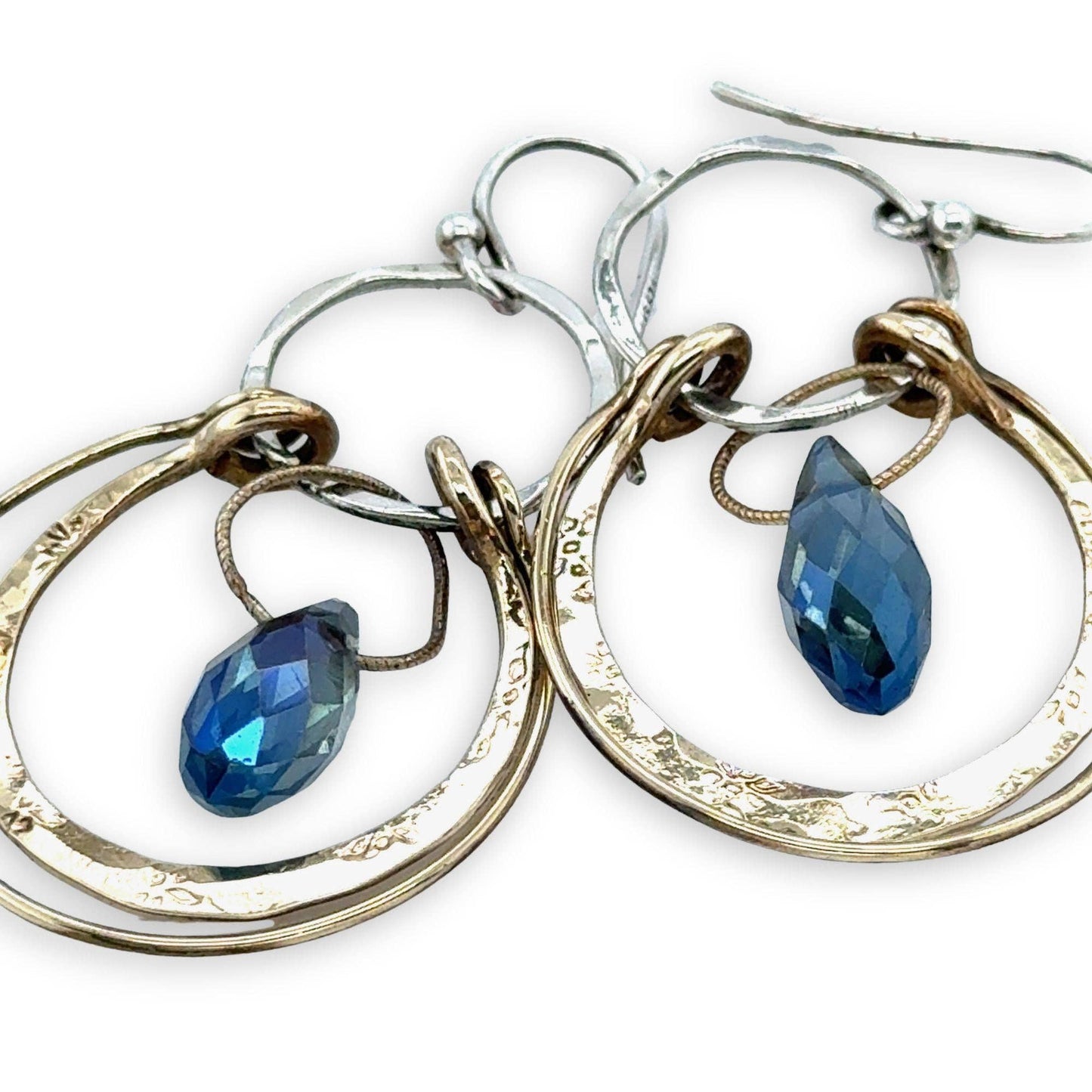 Pair of hoop earrings with blue teardrop charms on a white background