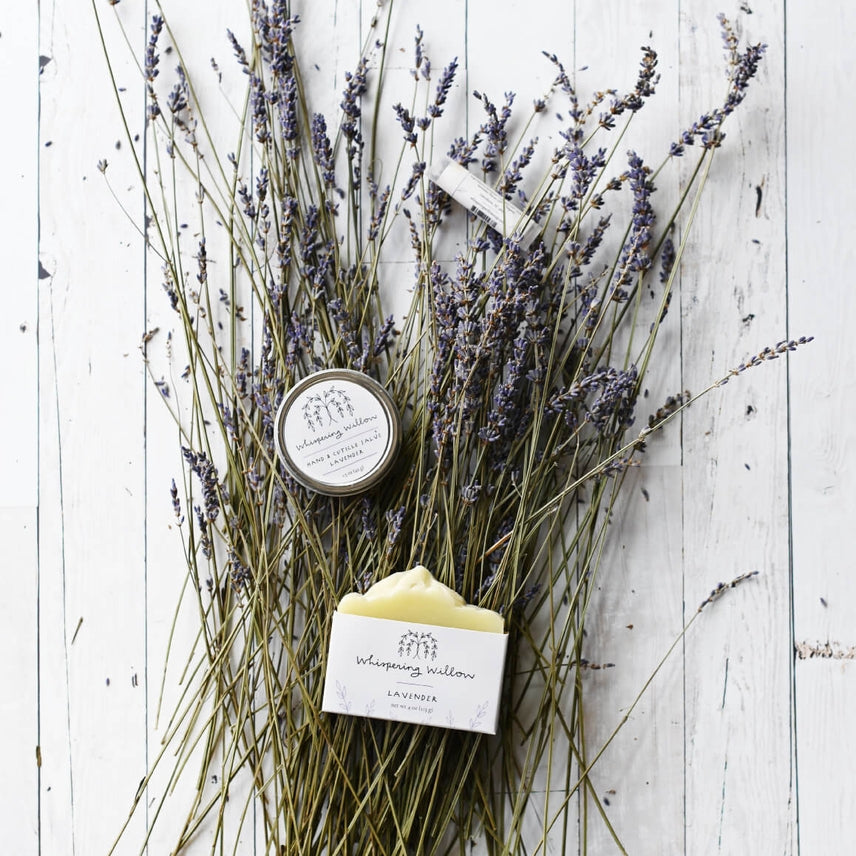 Lavender flowers with a tin of salve and bar of soap on a wooden surface