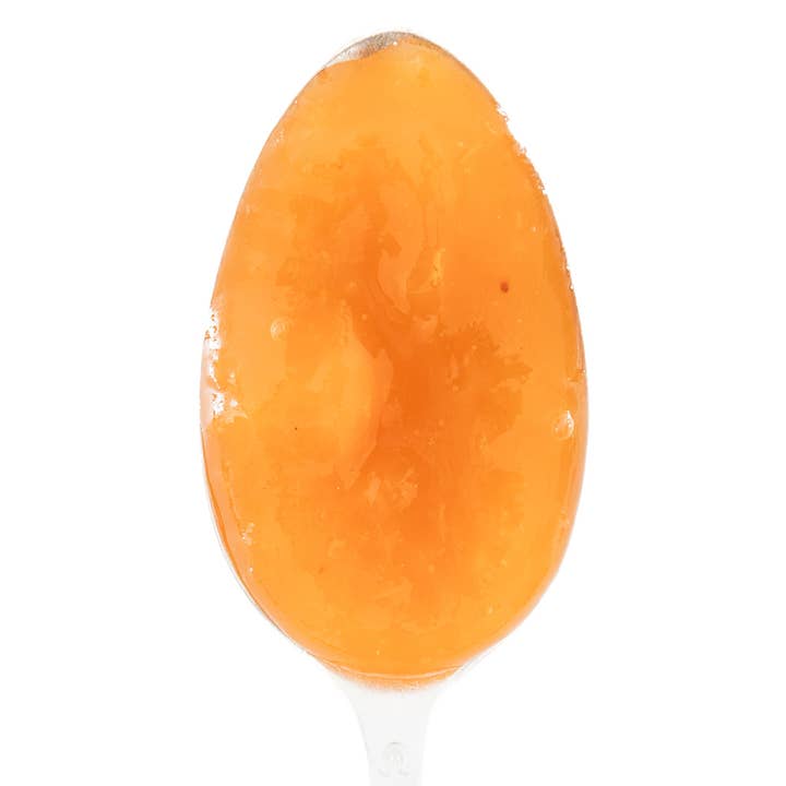 A spoonful of peach preserves on a white background.