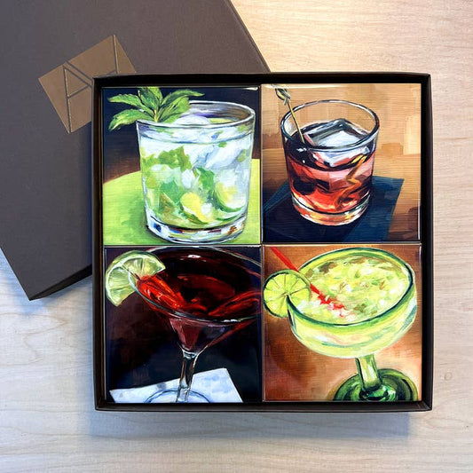 Four cocktail illustrations in a gift box on a wooden surface