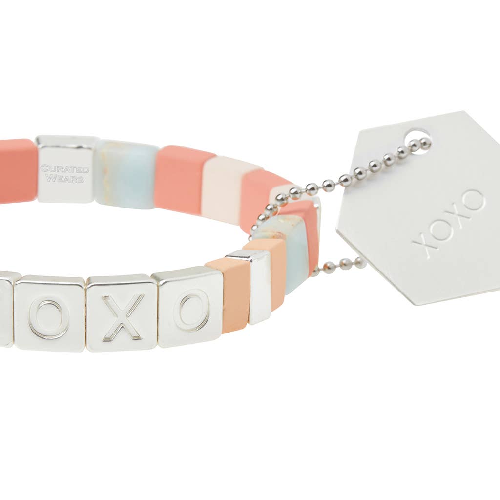 Bracelet with 'XO' charms and a branded tag on a white background