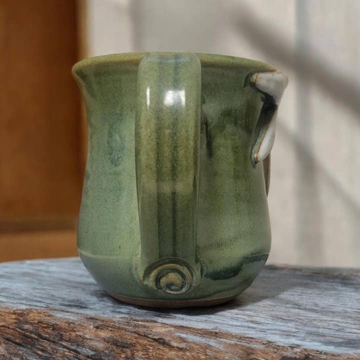 Green ceramic mug on a wooden surface with a blurred background