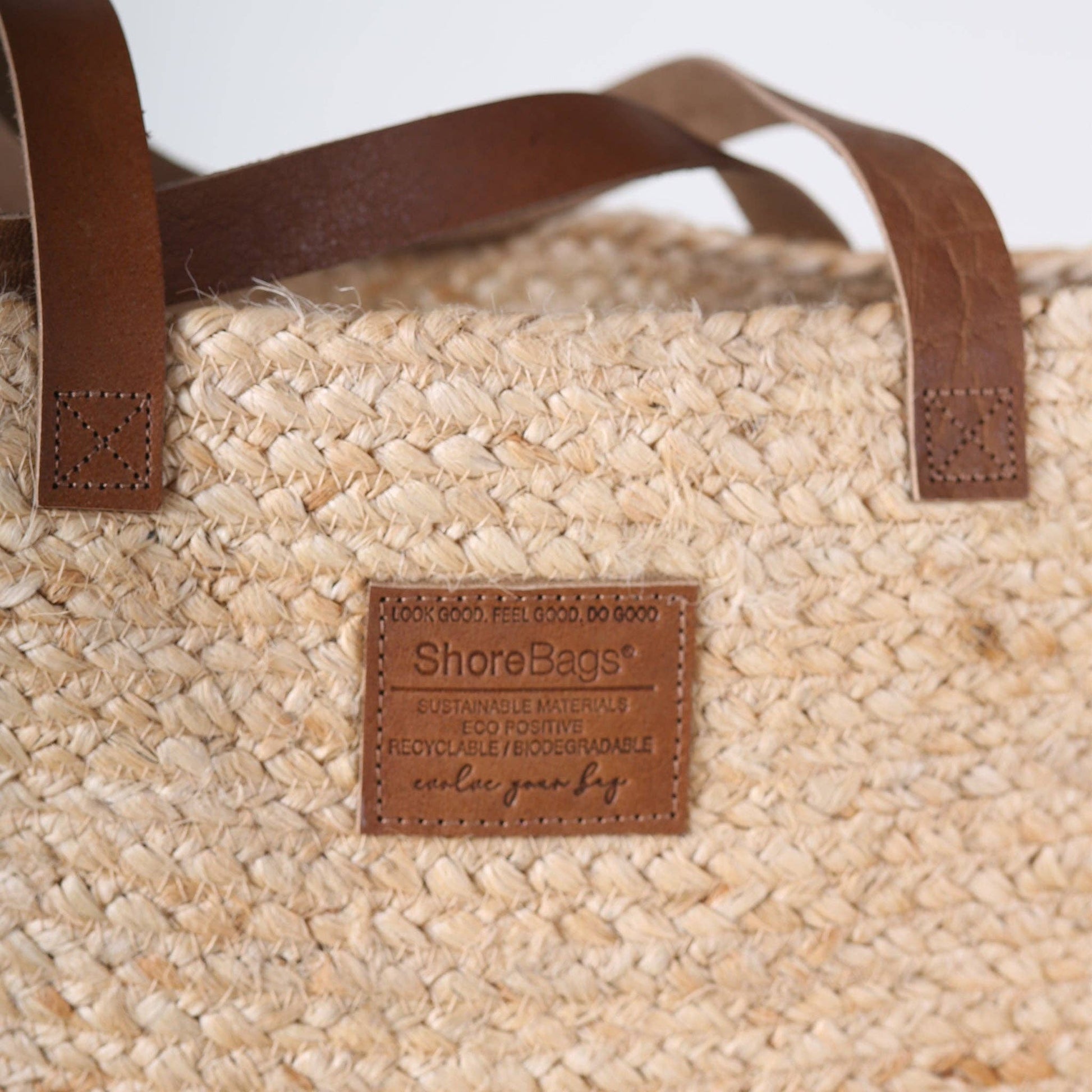 Woven bag with brown leather handles and ShoreBags label on a light background