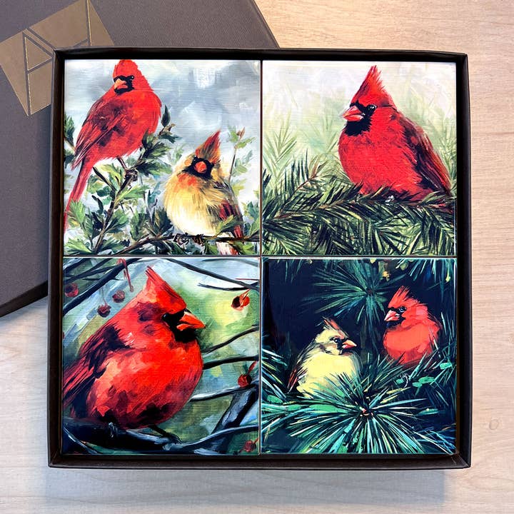 Coasters with cardinal illustrations in a gift box on a wooden surface.
