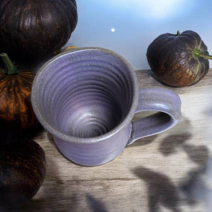 Purple ceramic mug on a wooden surface with pumpkins in the background. All images associated with this product listing show the same mug from various angles. The design is only on one side of the mug.