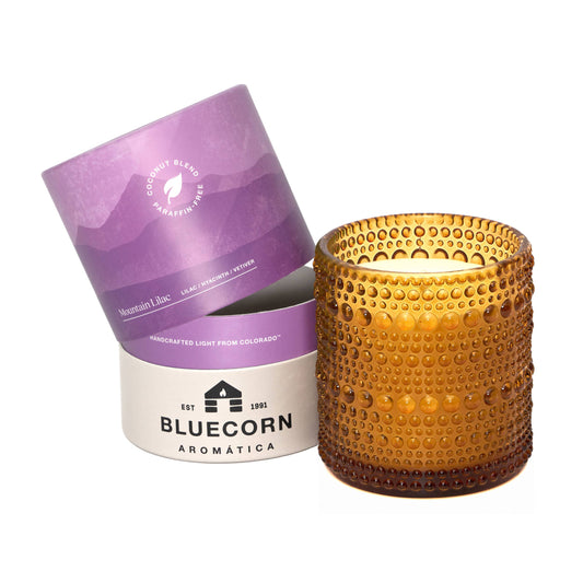 Amber textured candle with purple and white packaging on a white background
