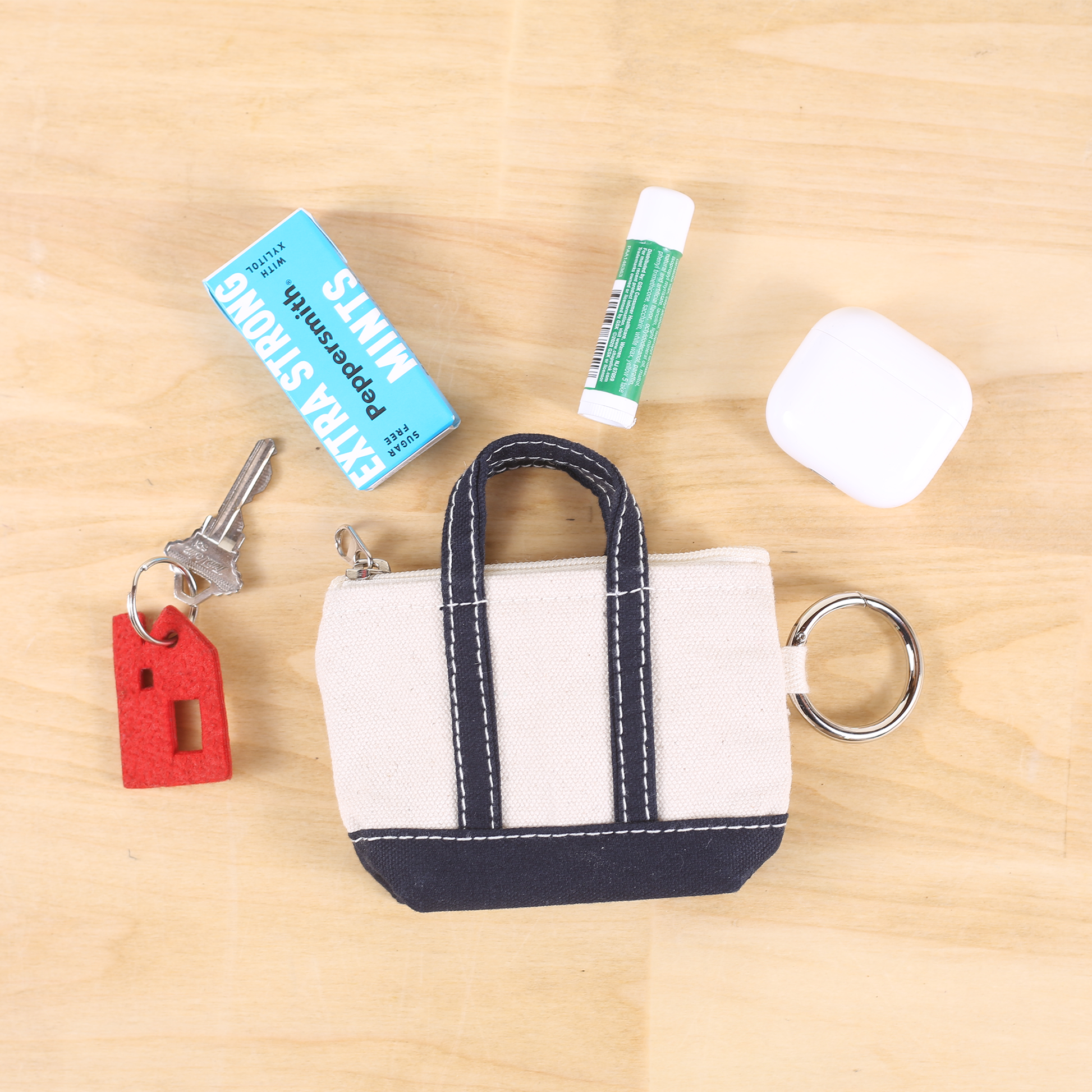 Small keychain purse with lip balm, mints, and key on a wooden surface