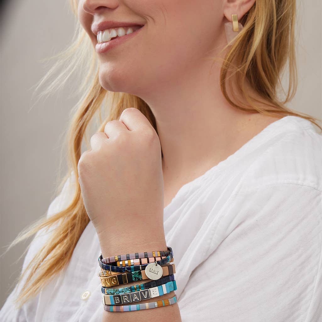 Woman wearing colorful bracelets on her wrist with a neutral background