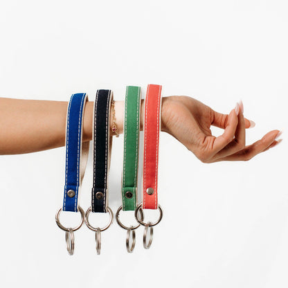 Four colorful keychains on a wrist against a white background