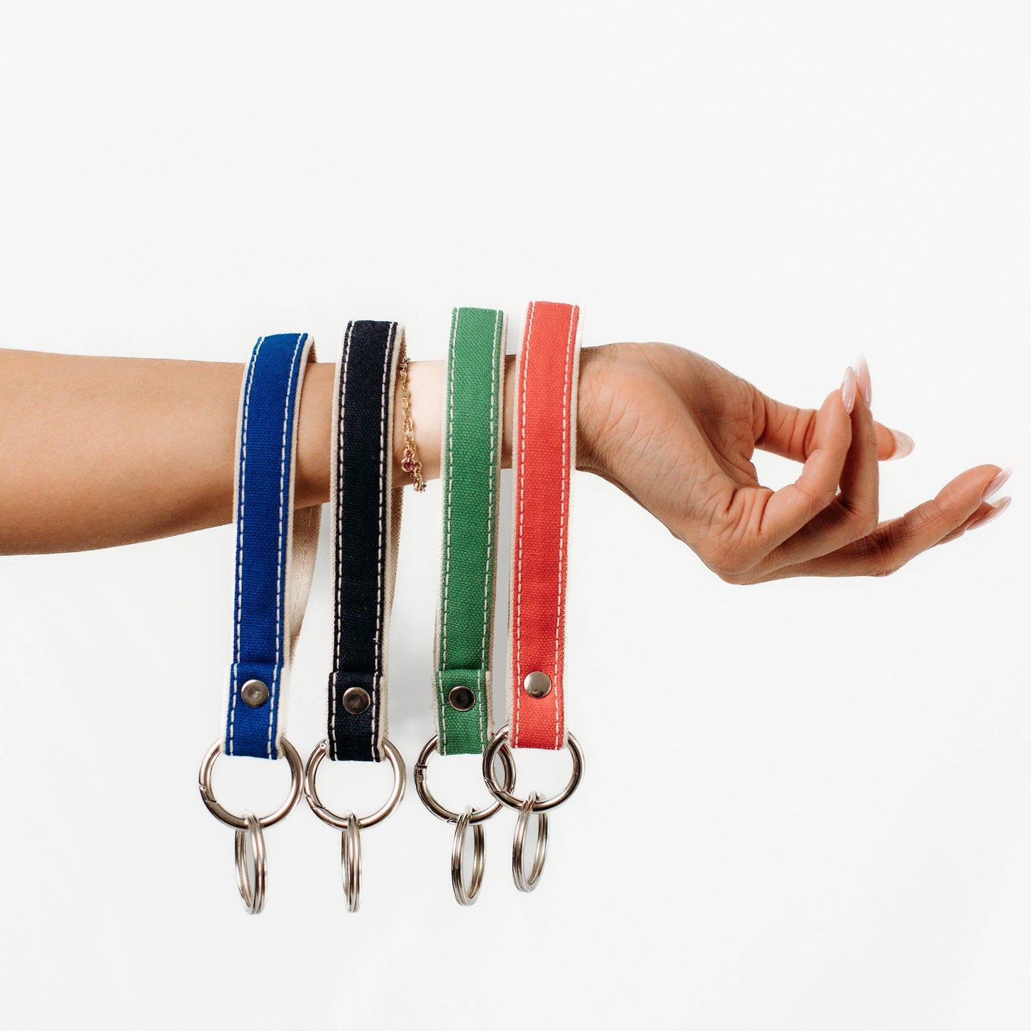 Four colorful keychains on a wrist against a white background