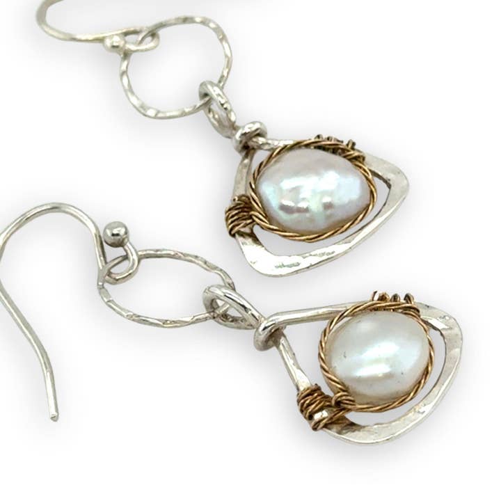 Pair of pearl earrings with silver and brass accents on a white background