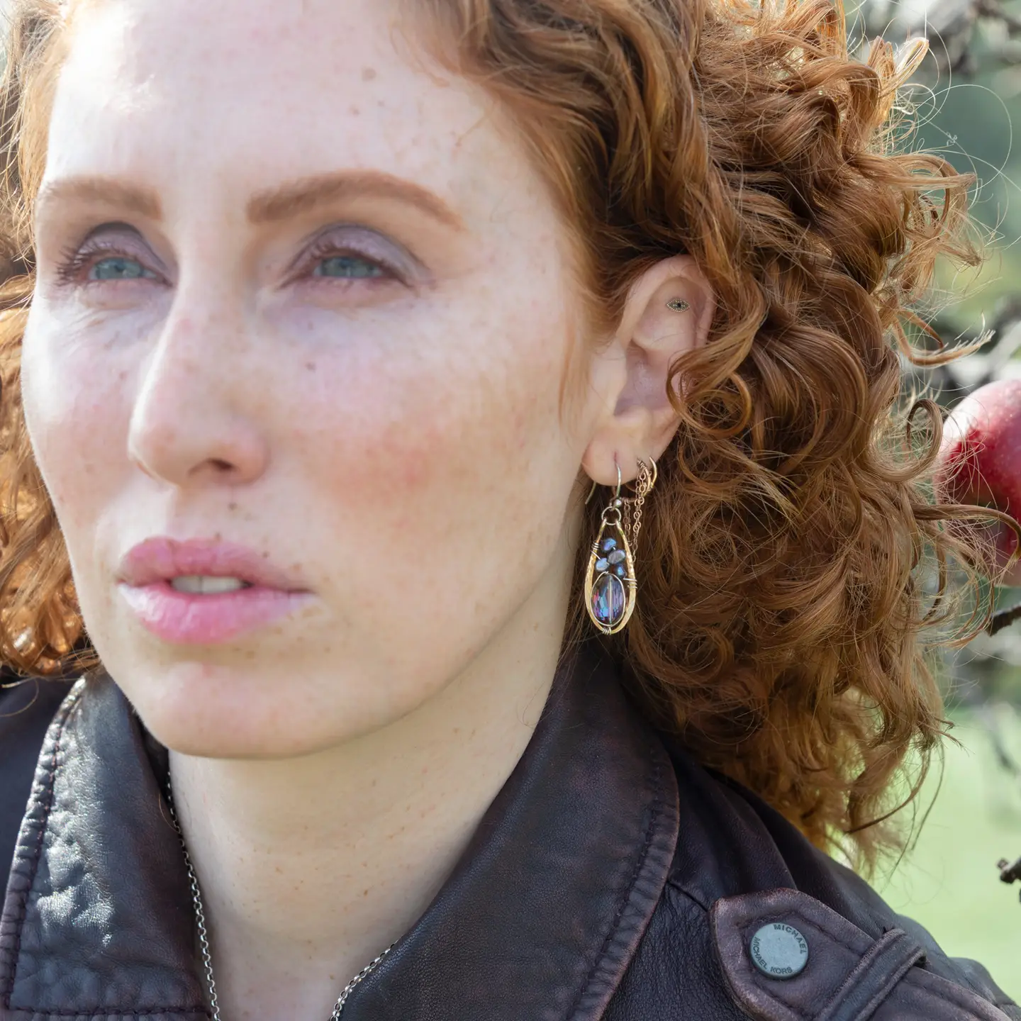 Close-up of a person with curly hair wearing earrings outdoors