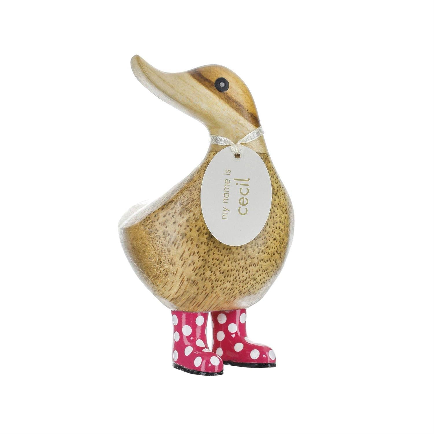 Wooden duck figurine with a tag and pink polka dot boots on a white background
