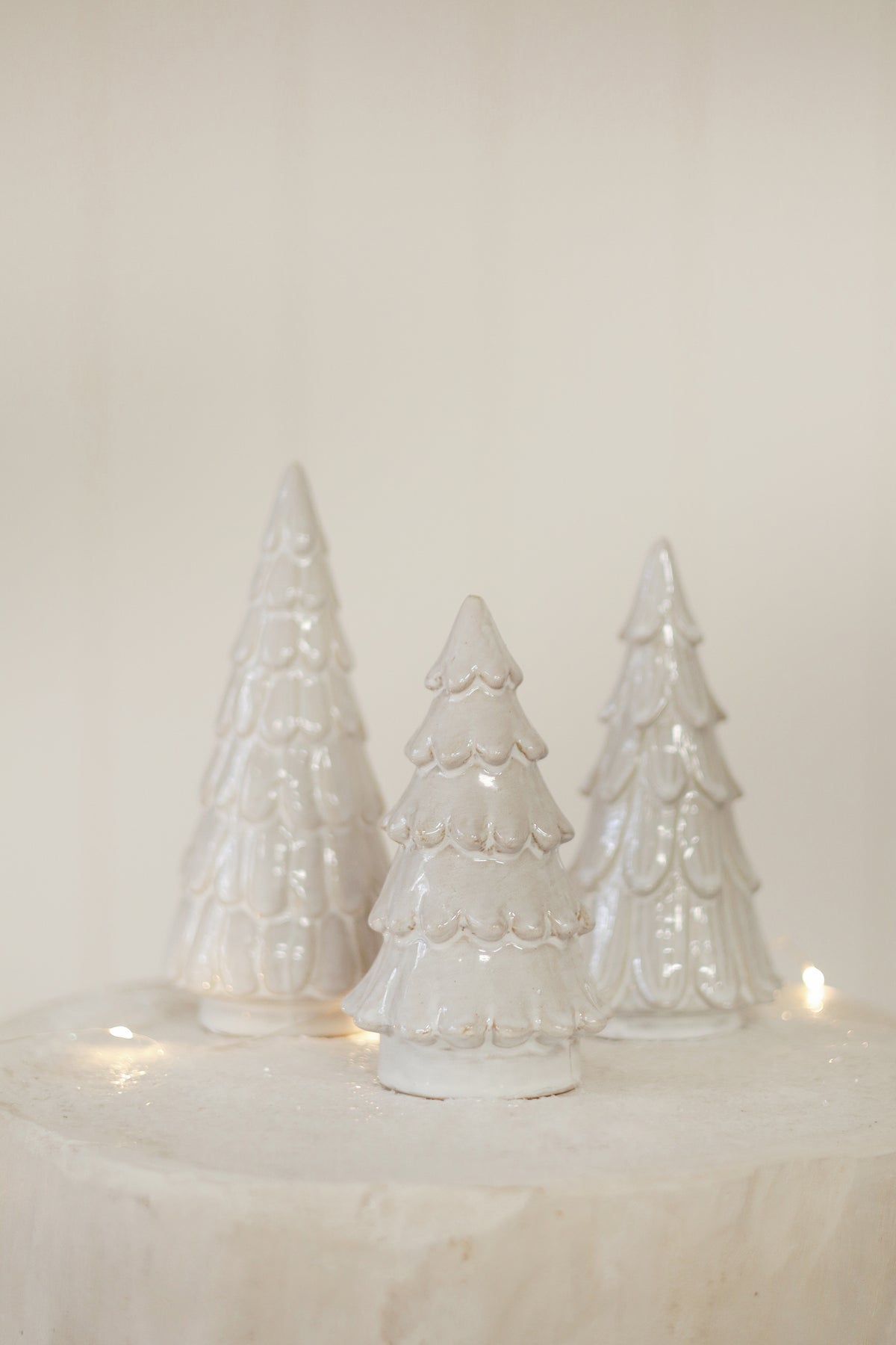 Three white ceramic Christmas trees on a light background