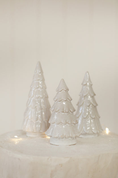 Three white ceramic Christmas trees on a light background