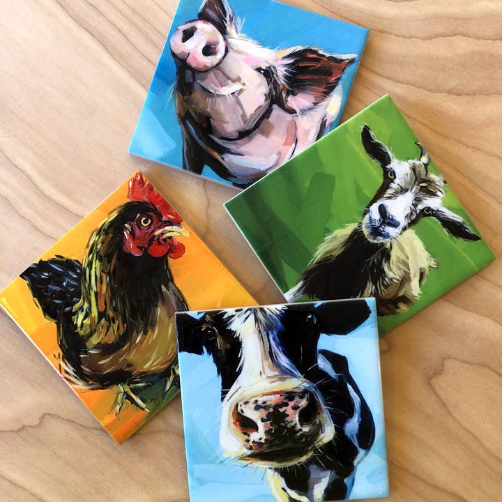 Four square coasters with colorful animal portraits on a wooden surface.