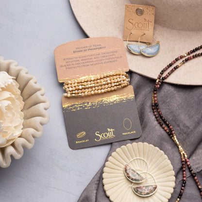 Jewelry set including bracelet, necklace, and earrings on Scout branded cards with a decorative background.
