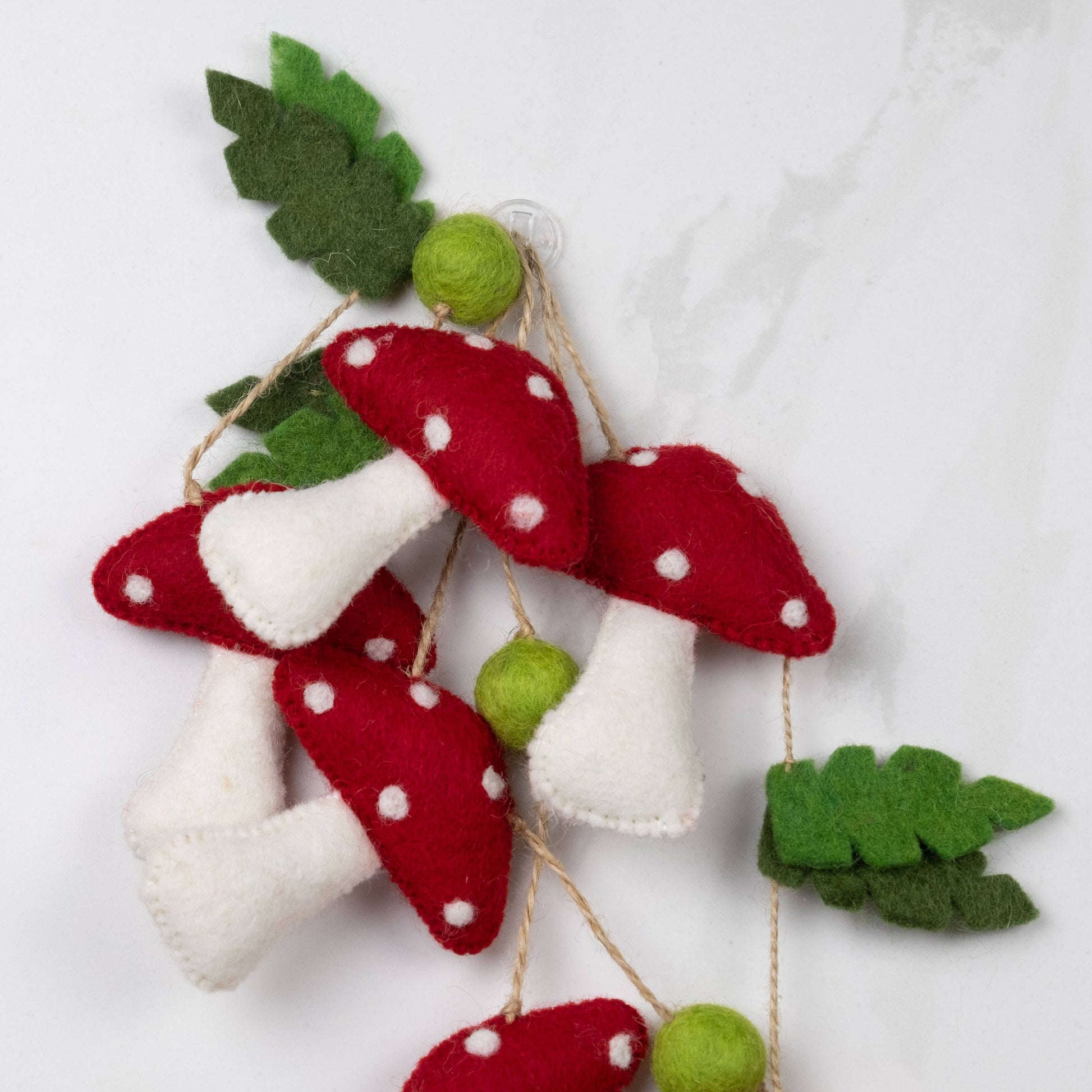 Felt mushroom decorations with green leaves on a white background