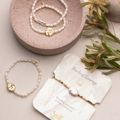 Pearl bracelets with gold accents on a beige surface with a 'Scout' branded card.