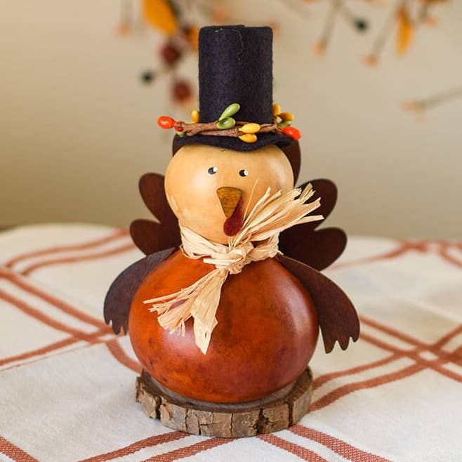 Decorative gourd turkey with a top hat and straw on a patterned surface