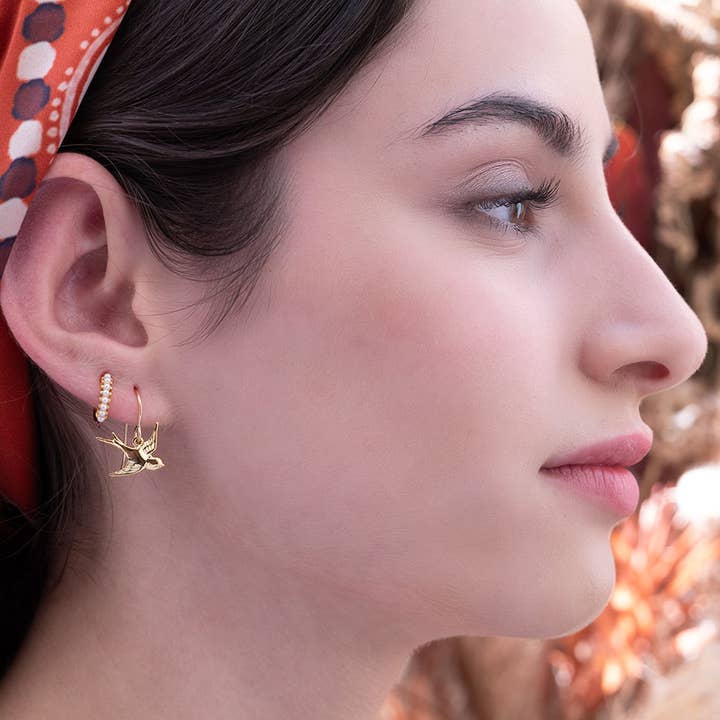 Close-up of a woman wearing gold earrings with a blurred background
