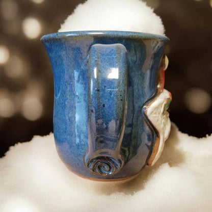 Blue ceramic mug with a face design on a white surface