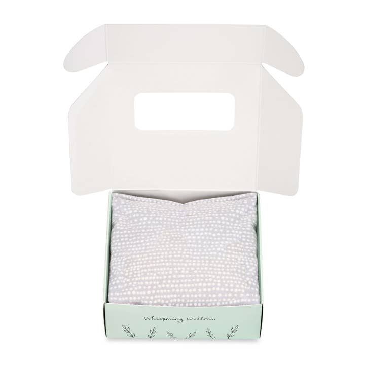 Open product box with eye pillow inside on a white background.