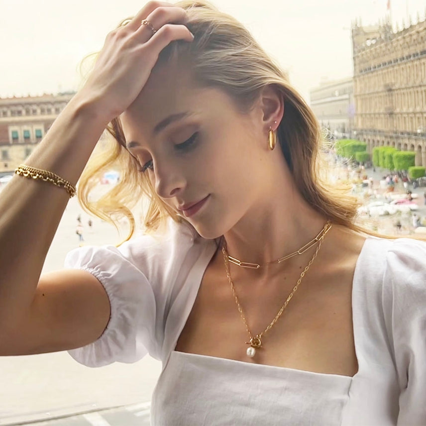 Woman wearing gold jewelry with a blurred cityscape in the background