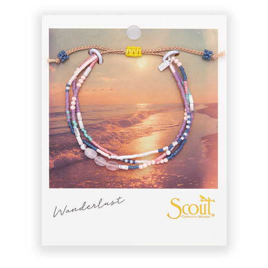 Multistrand beaded bracelet on a card with 'Scout' branding and 'Wanderlust' text, set against a beach scene.