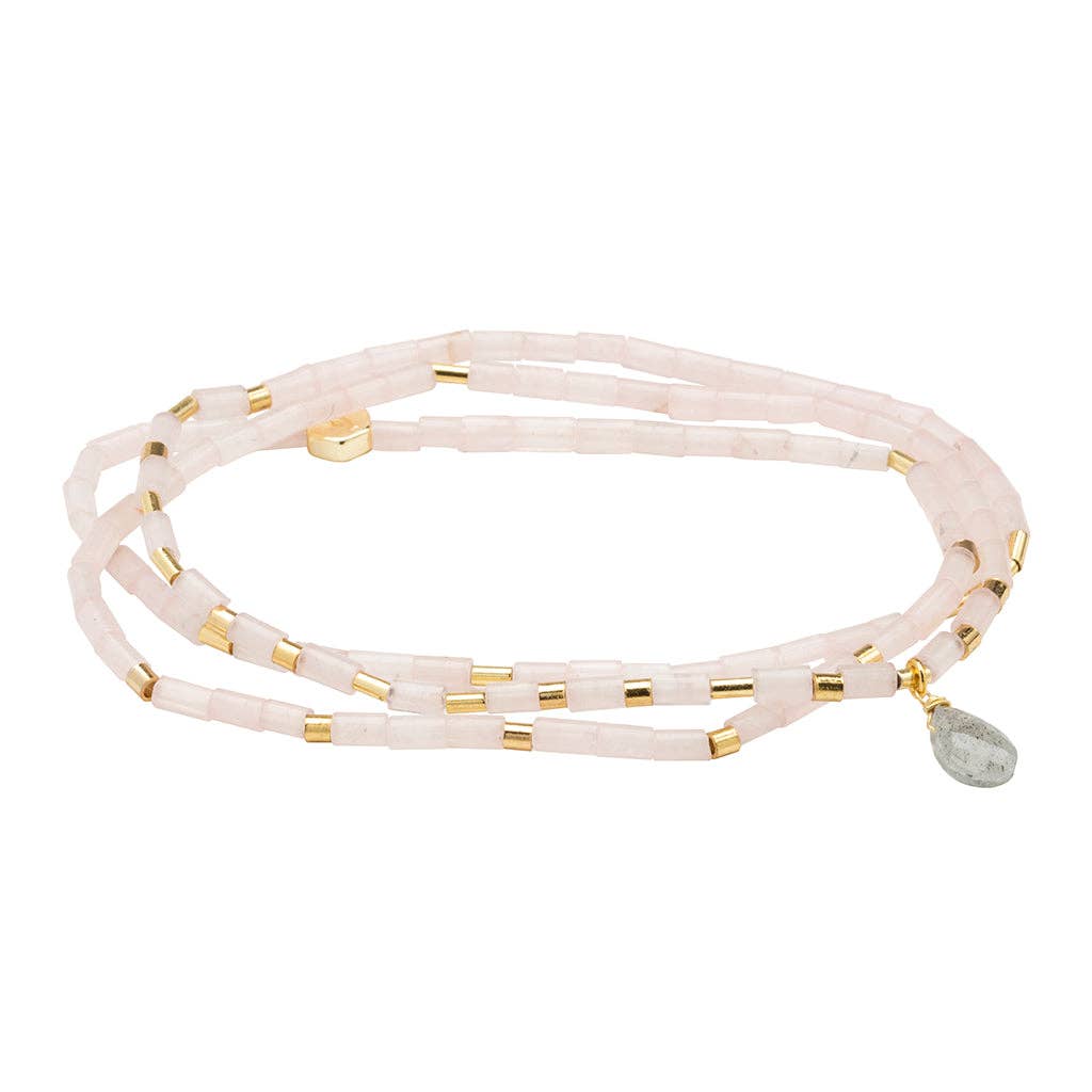 Multi-layered bracelet with gold accents and a gray bead on a white background