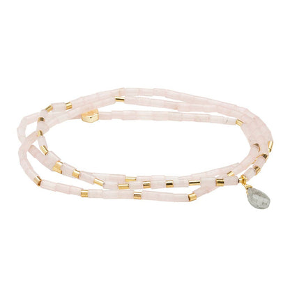 Multi-layered bracelet with gold accents and a gray bead on a white background