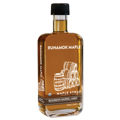 A bottle of Runamok Maple Bourbon Barrel-Aged maple syrup with a black cap and a brown label featuring white barrel illustrations, shown on a plain white background.