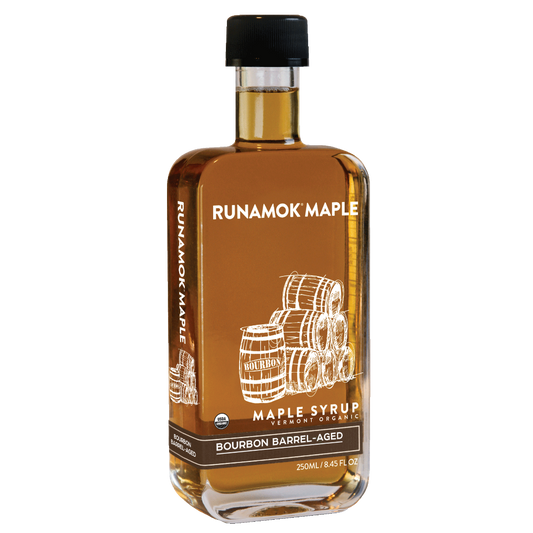 A bottle of Runamok Maple Bourbon Barrel-Aged maple syrup with a black cap and a brown label featuring white barrel illustrations, shown on a plain white background.