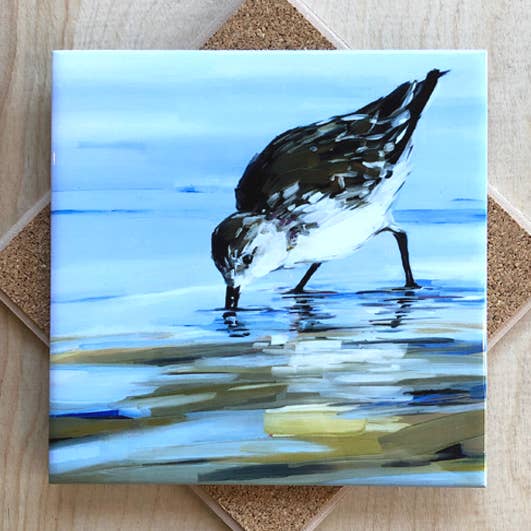 Trivet with painting of a bird wading in water on a textured surface.